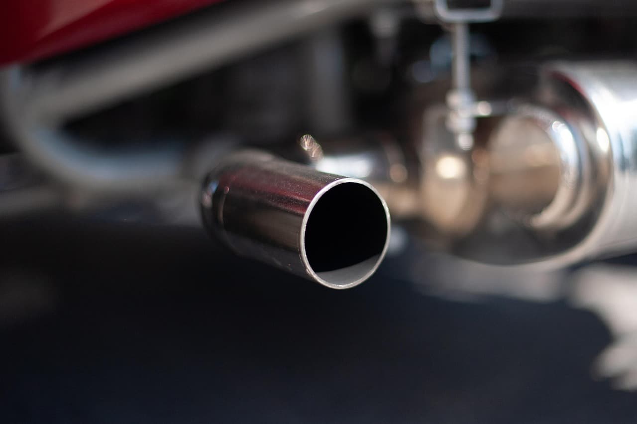 A polished exhaust tailpipe under a car, close up